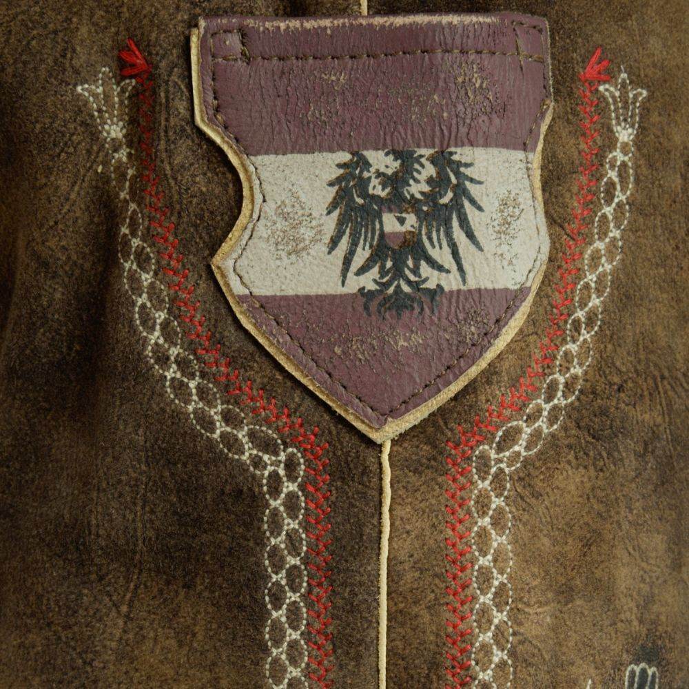 Leather patch on lederhosen with embroidered motif and stitched leather border