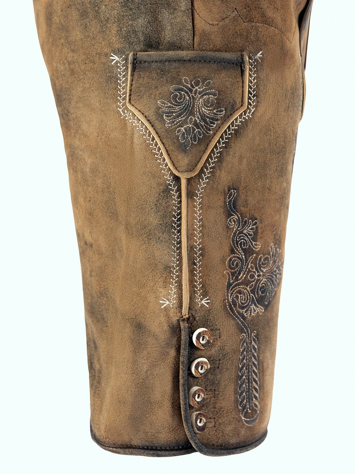 Men's short lederhosen close-up with decorative embroidery, lace trim, tan-brown buttons