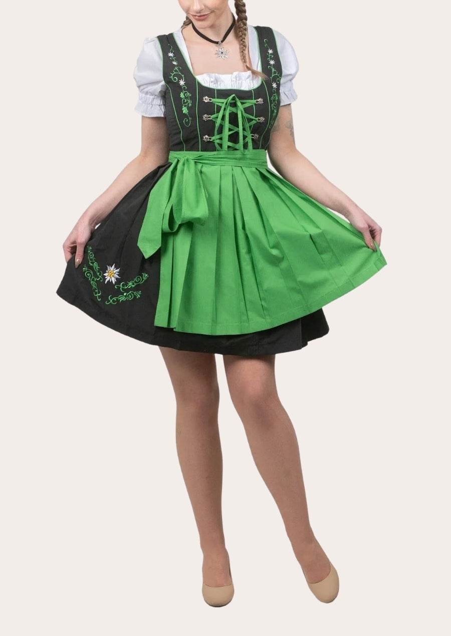 Dirndl dress on model: white puff sleeves, green waist tie, black bodice and green skirt with apron