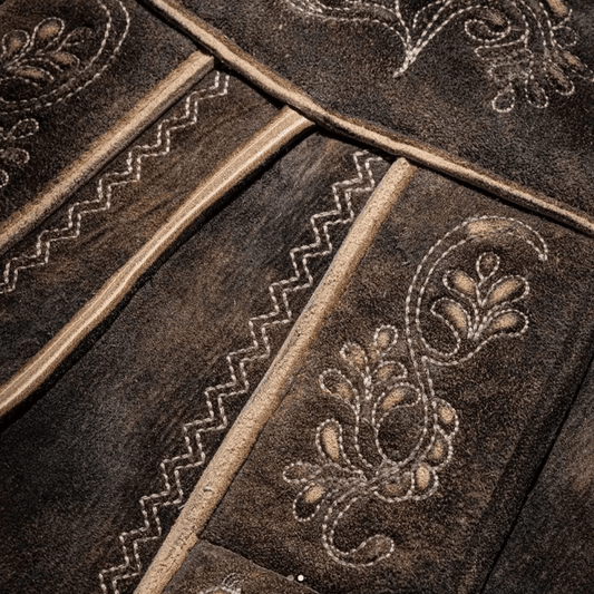 Close-up of deer-leather lederhosen embroidery with beige trim and floral ornament panels